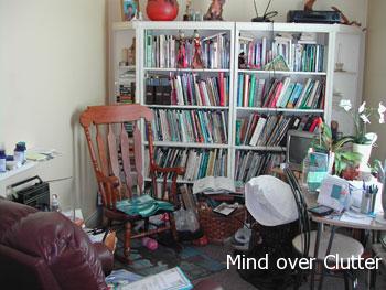 A messy small apartment with books. plants, papers on the floor 