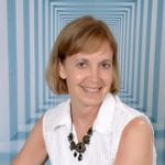 A blue and white striped tunnel in the background with Julie Stobbe in the foreground wearing a white blouse.