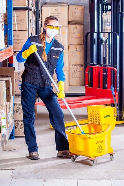A woman in a uniform with cleaning supplies 