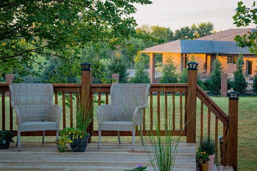 Backyard deck with a grey chair and brown wooden fence and lovely green plants 