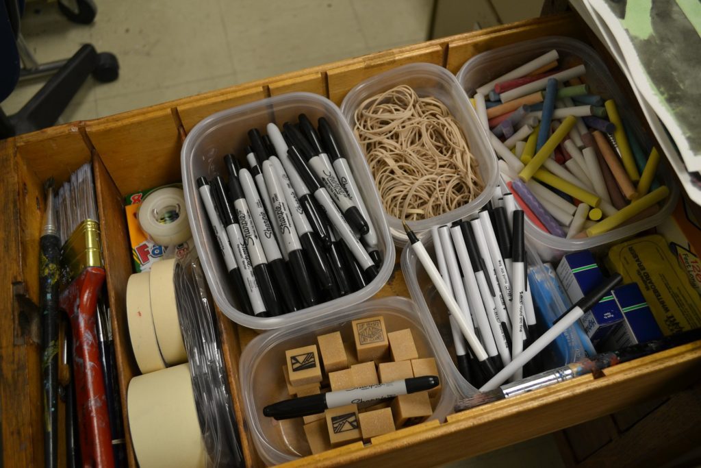 A well organized office drawer with markers, tape elastics, stamps