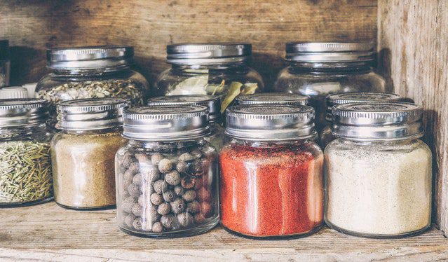 uniform small mason jars unsed for spices sitting on a shelf. 