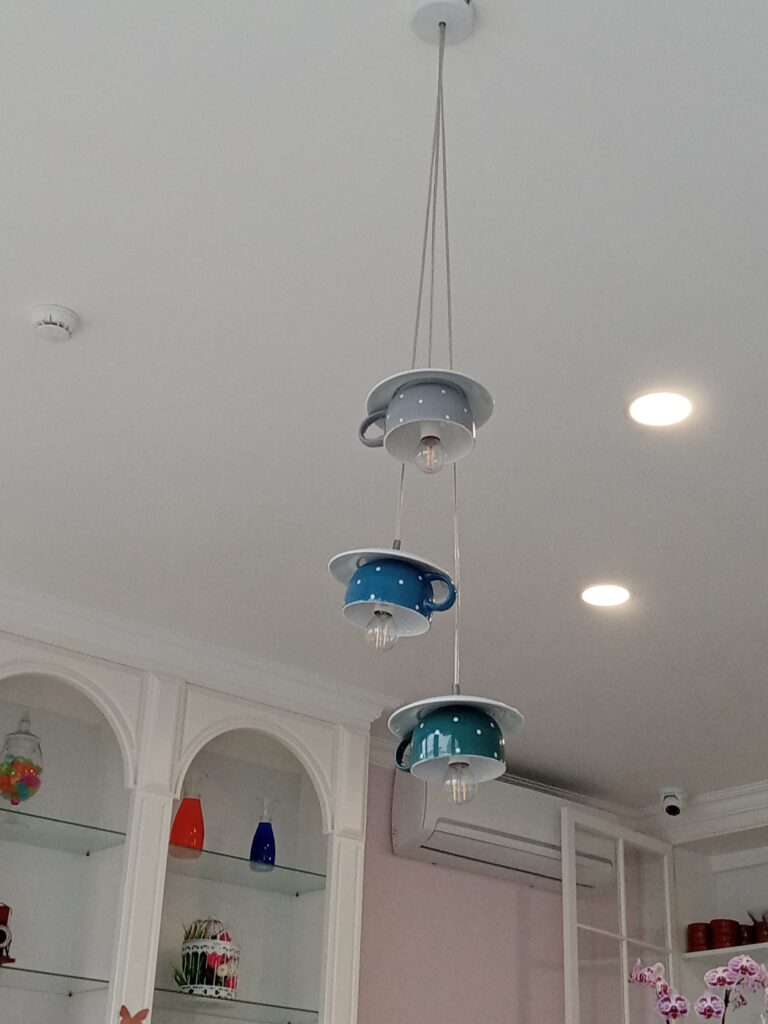 Tea cups hanging upside down as lamp shades from a ceiling.