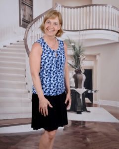 Julie Stobbe standing in an entryway in front of a spiral staircase. 