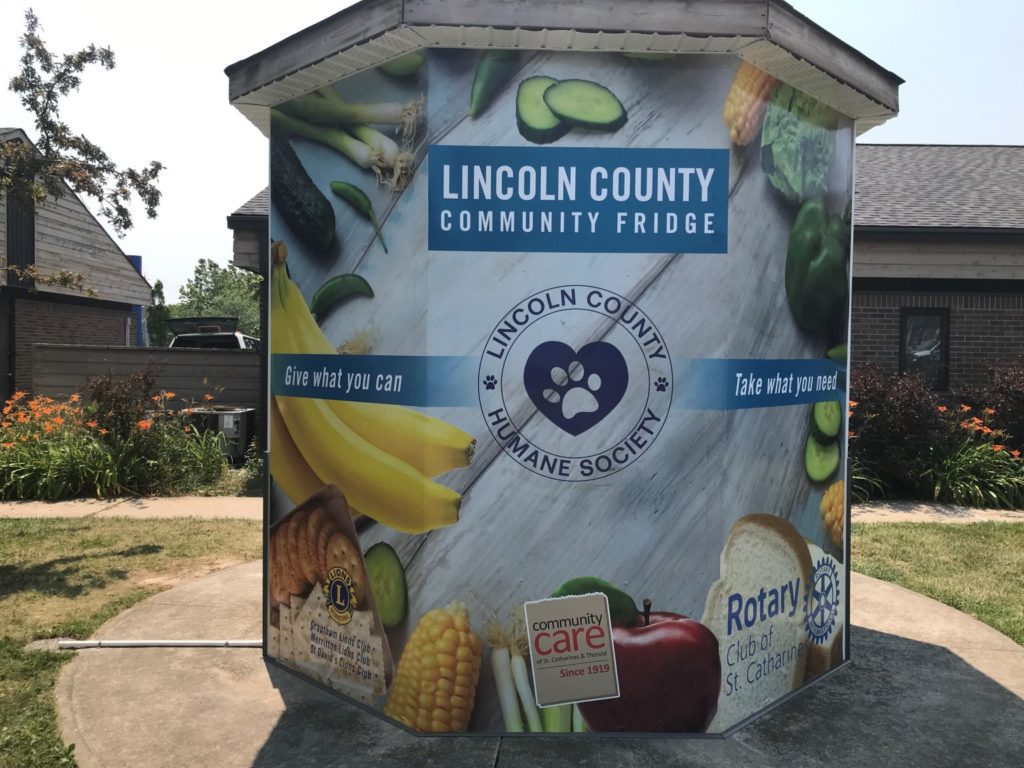 A large cupboard sitting on the side walk to take donations of food.