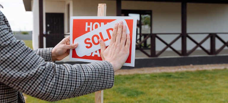 A person putting a sold sign for a house.