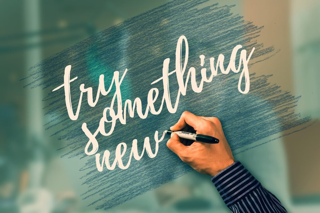 a hand writing a sign saying try something new. 