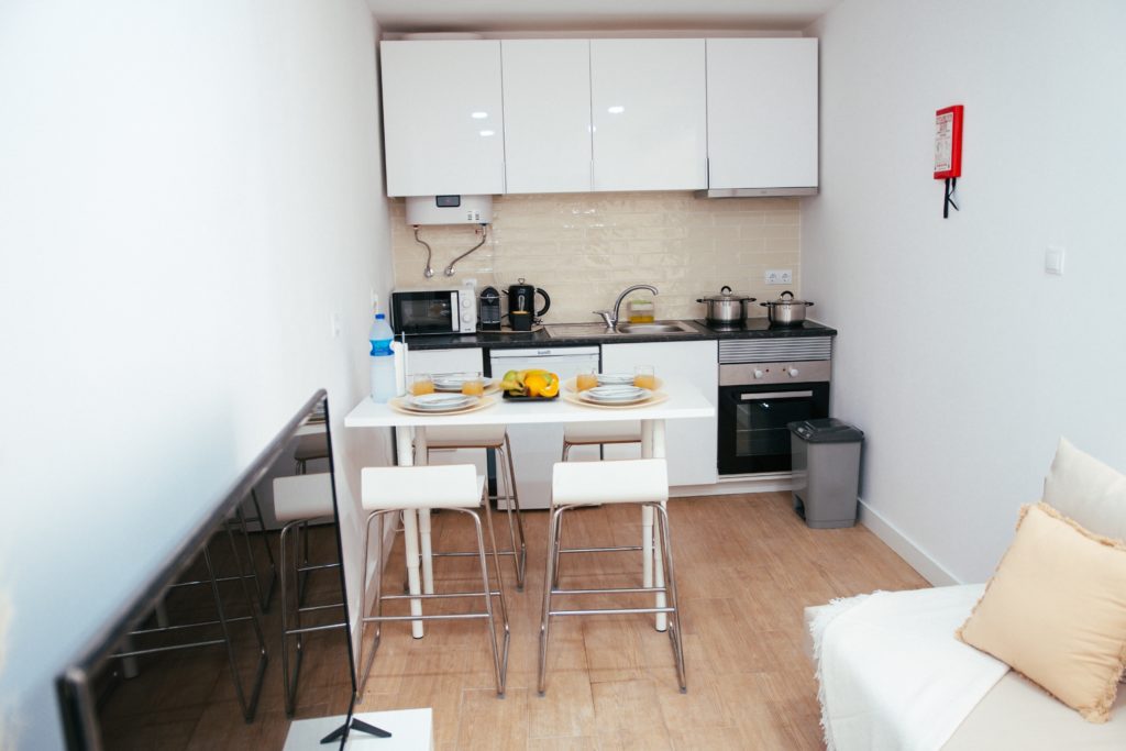 Studio apartment with a galley kitchen, small table with 4 stools and a couch that becomes a bed. 