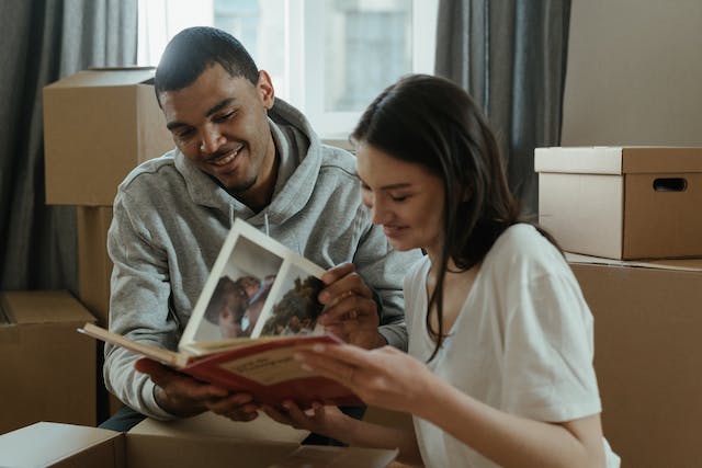 A couple surrounded by boxes looks at a family photo album.