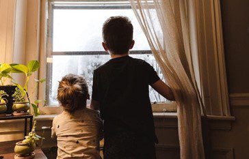 2 boys looking through a window