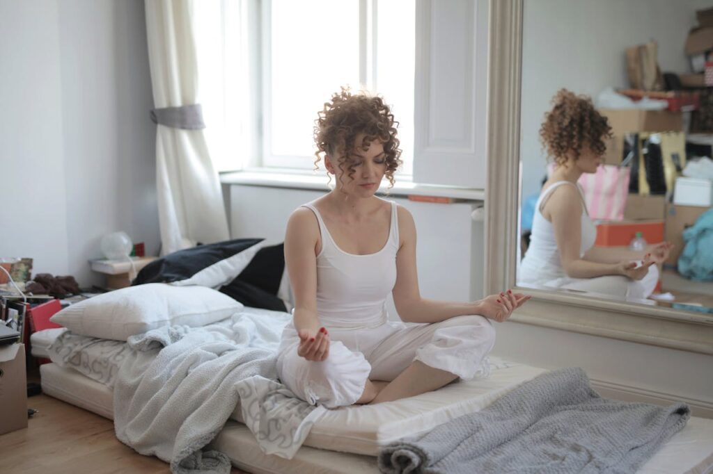 A woman meditating on her bed while overcoming hoarding