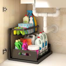 A 2 tier brown shelf with a larger bottom and a half shelf on top to fit beside the plumbing under the sink. 