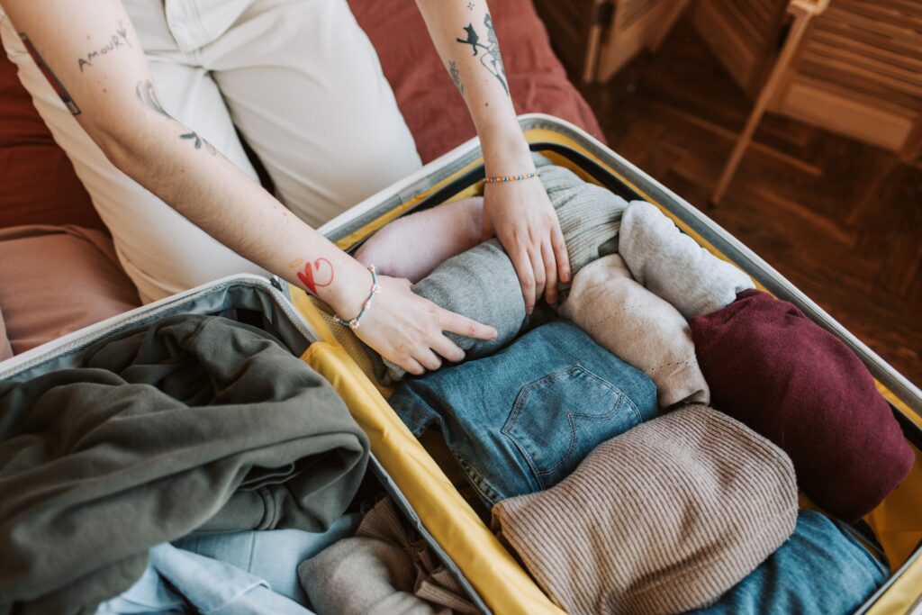 A women rolling clothes a nd place them in a suitcase. 